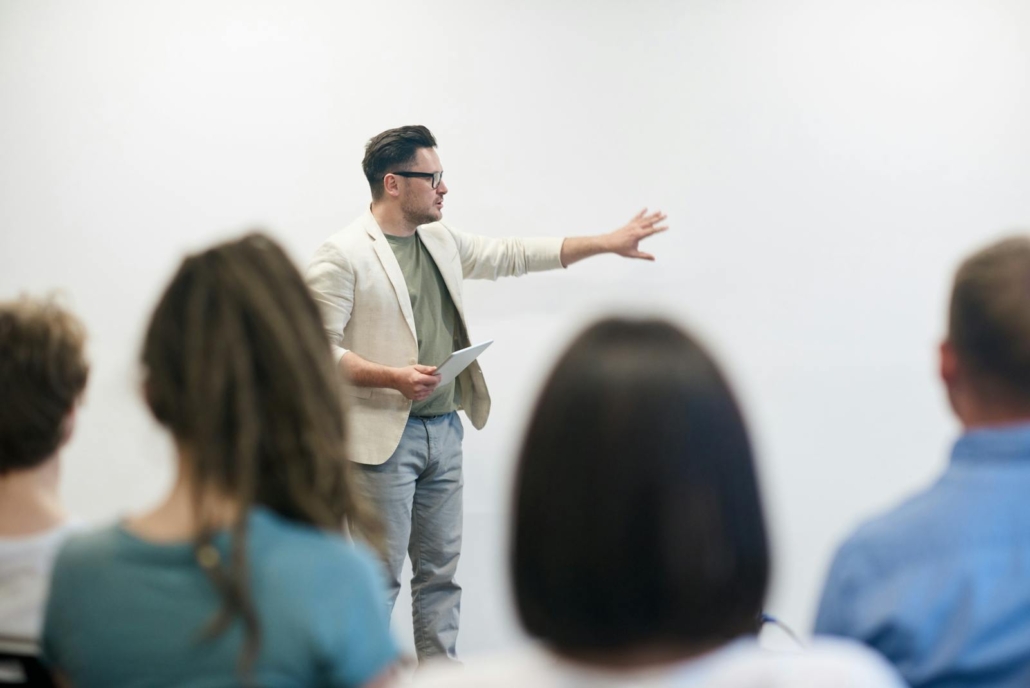 Leadership coach demonstrating communication hacks to a group of professionals during a team workshop.