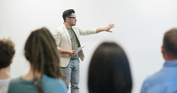 Leadership coach demonstrating communication hacks to a group of professionals during a team workshop.